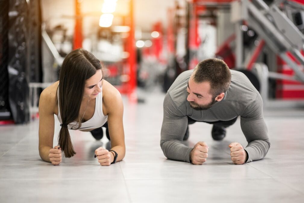 Un hombre y una mujer hacen el ejercicio Plank, diseñado para todos los grupos musculares